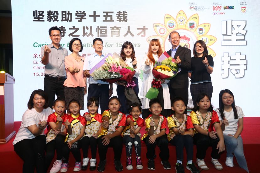 （后排左起）巴力吉利令华小家协副主席张国明先生、巴力吉利令华小校长黄素花女士、巴力吉利令华小董事长梁雅育先生、教育部副部长YB张念群、一年一校爱心大使宇田、马来西亚余仁生董事经理邱月辉先生及 Melody节目经理丘咏欣小姐与巴力吉利令华小师生合照留念。