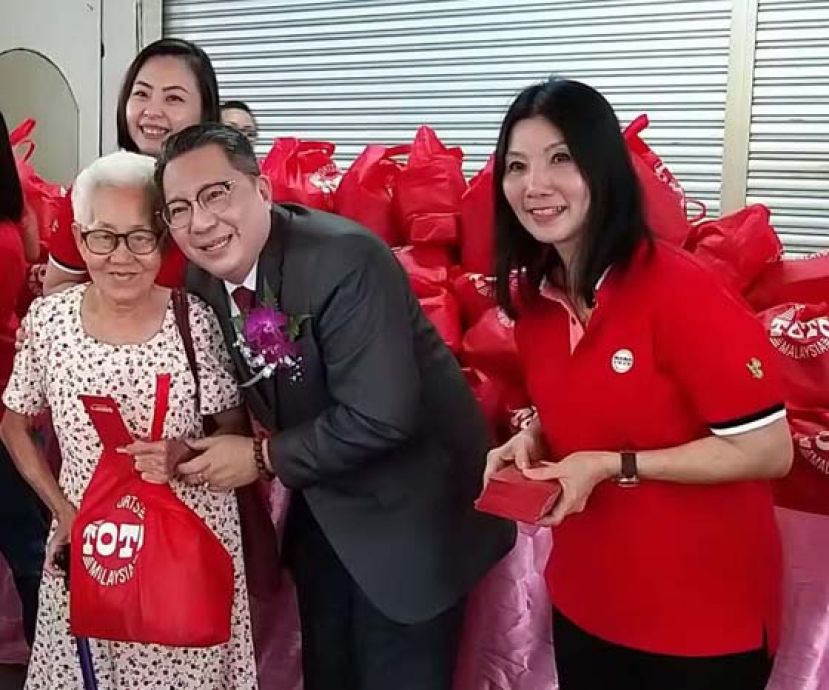 古晋南市市长拿督黄鸿圣（右二）移交红包及礼包予受惠贫老时摄，右一为多多博彩古晋区营销执行员陈培真及多多博彩东马区经理黄淑妮（后排）。