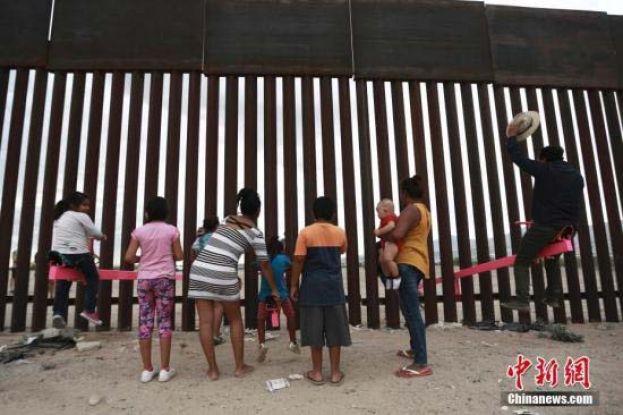 美国加州两位教授利用美墨边境高墙的空隙，设置了横跨两国的跷跷板，跷跷板一边在美国，一边则在墨西哥，让美墨两边的大人小孩隔着高墙仍能一同玩耍。