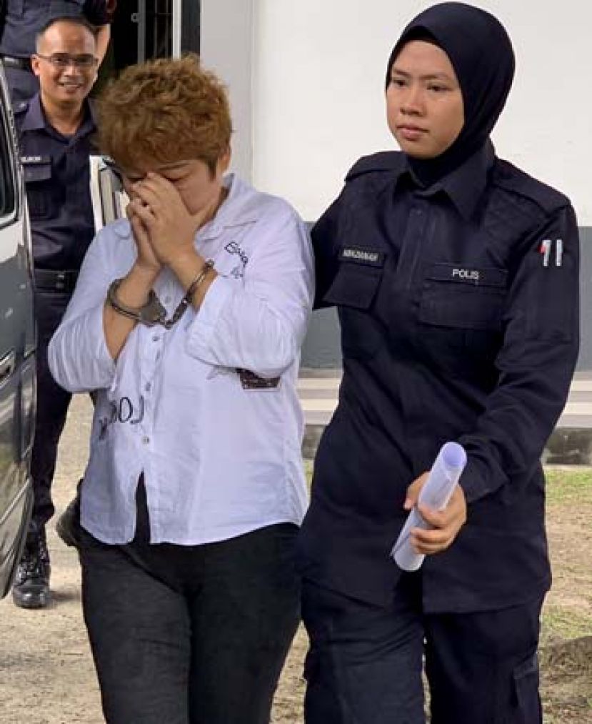 中国女子面对两项欺骗控状不认罪，带往诗巫监牢时双手掩面，避免露出面貌。