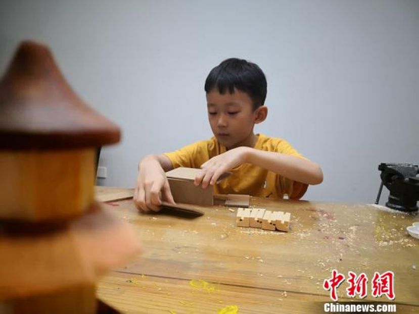 7岁的李轩锐正在搭建圆榫盒子。