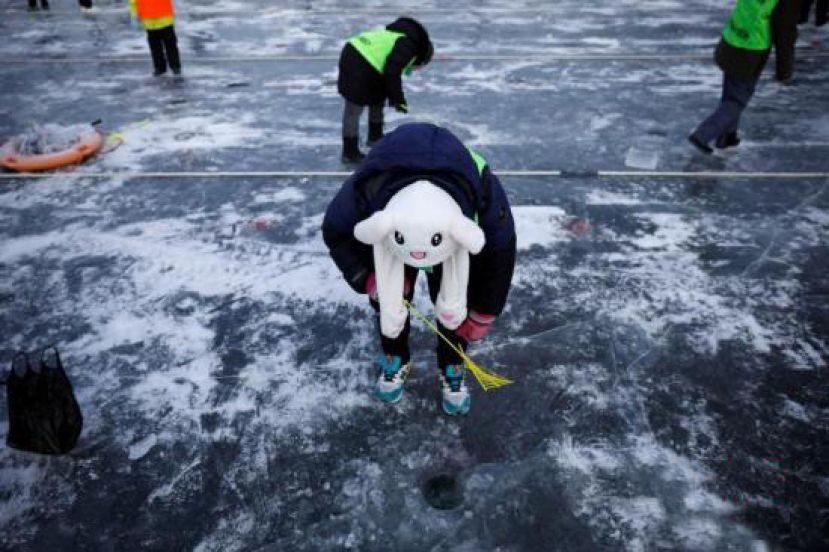 图示：游人在观察钓鳟鱼的冰洞。