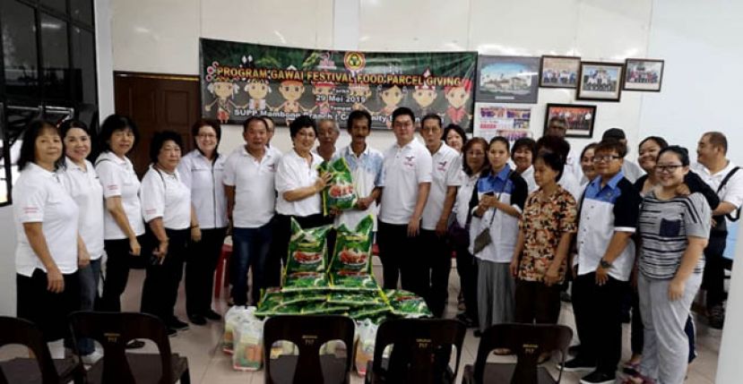 人联党曼旺支部主席拿汀徐美丽（前排左七）分发布施品给受惠者。