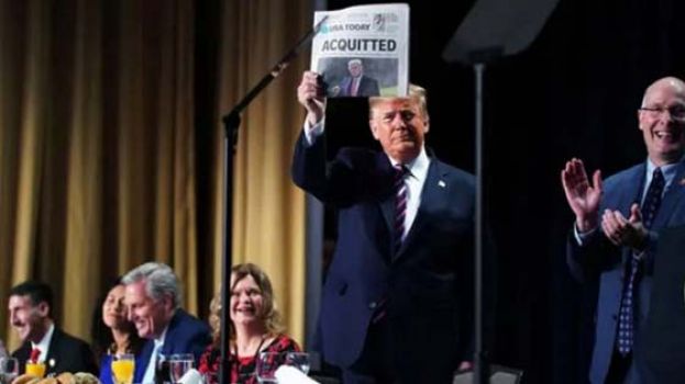 特朗普高举标显用大号字写著&ldquo;无罪&rdquo;的报章。