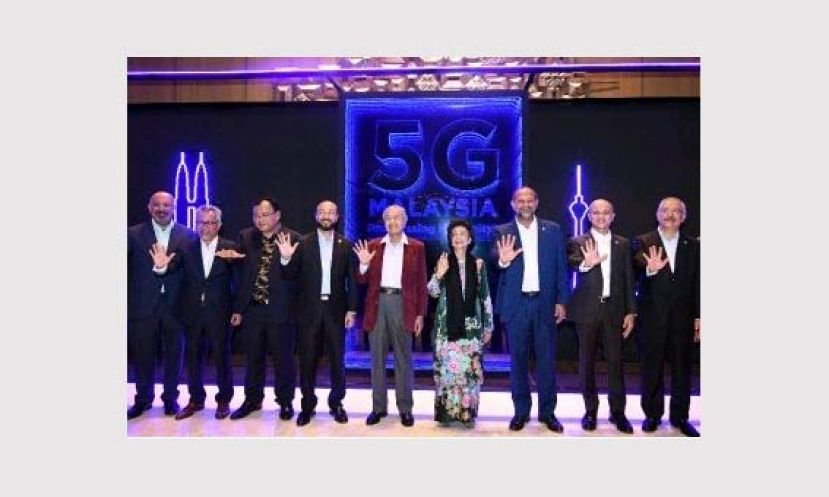 首相敦马哈迪(左5)与一众嘉宾比出象征&ldquo;5G&rdquo;的手势，标志浮罗交怡的5G大马示范项目正式启动。