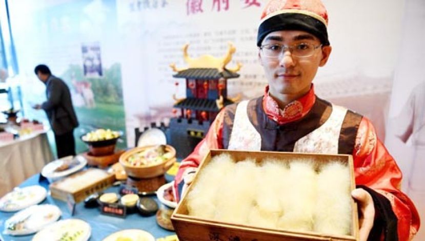 图示：美食推荐人员展示徽菜第一怪──毛豆腐。