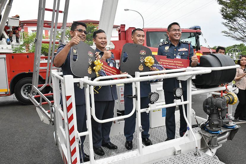 砂消防与拯救局局长凯鲁丁（右一）移交2台云梯消费车予2间消防局局长。