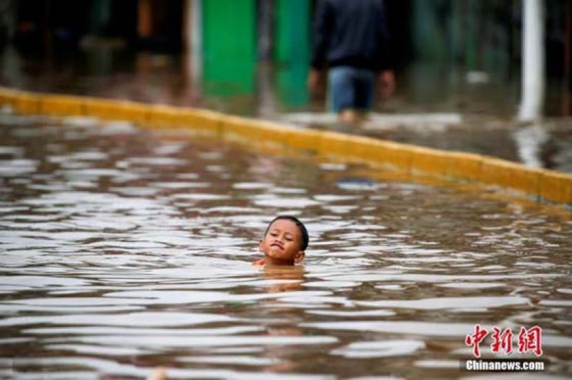 当地时间1月2日，印尼首都雅加达遭遇暴雨，雨后城市街道洪涝严重，大人忙着转移家中财务，孩子们在水中嬉戏玩耍，丝毫没有因为洪水影响心情。