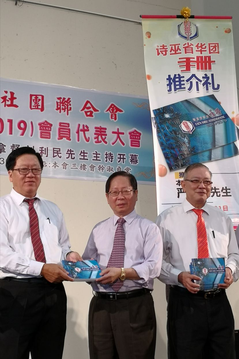 诗巫省华人社团联合会会长严黰胜(左)赠送手册给刘利民，右是署理会长刘锦虎。