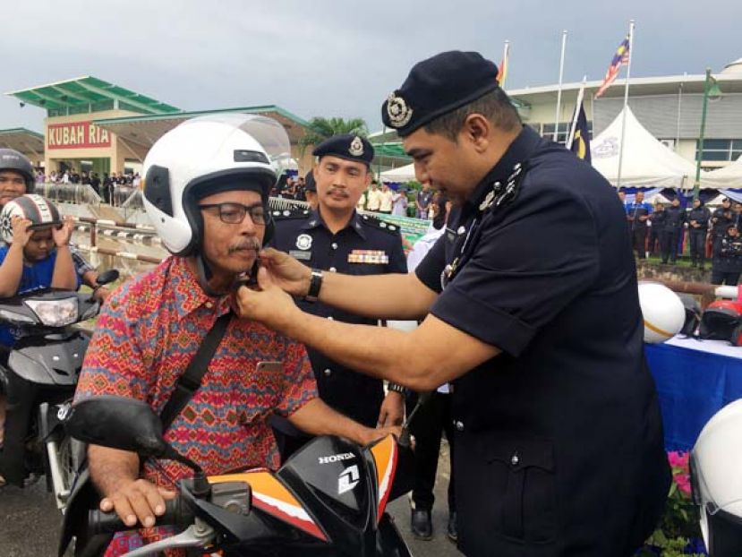 砂拉越防范罪案与社区安全组主任拿督莫哈末哈斯布拉为民众戴上安全头盔。