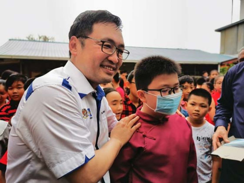 实丹宾国会议员张健仁（左）为一名字学生戴上口罩。