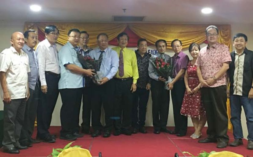 古晋中华小学校董会署理主席蔡文铎（左四）及四小副主席黄云华（右四）在主席王长福（左七）和执行顾问黄张金发（右六）等人见证下，分别赠送花束予贝荣栋校长及李美发主任；（左起）为五小副主席田招炎、四小监学吴孟墩、三小副主席郑文发、二小副主席张光福、四小副校长陈亚淑、秘书长田松茂及财政刘贵梦。