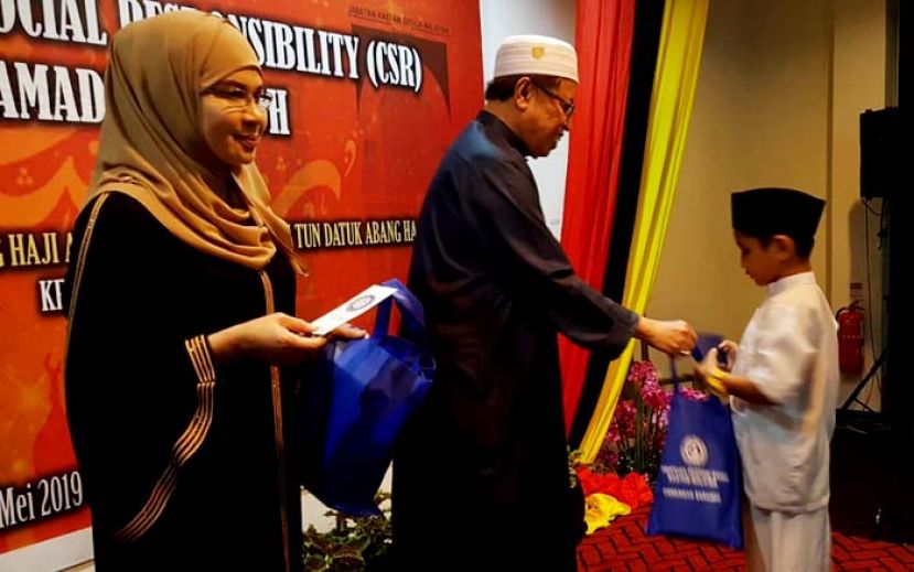 砂首长拿督巴丁宜阿邦佐哈里（中）在砂关税局局长拿督莎丽花哈丽玛（左）的陪同下，颁发礼包予儿童。