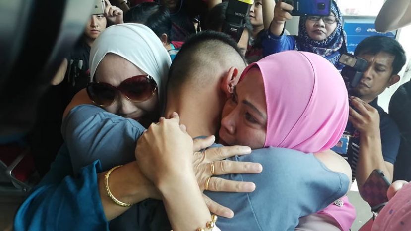 图示：青年与家人紧紧拥抱。