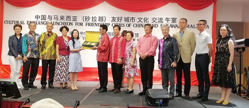 中国驻古晋总领事程广中(左六)赠送纪念品给予古晋南市市长拿督曾长青的代表许德婉(右八)，左起为张阳夫人胡春晖、晋汉连省华总副会长本固鲁陈传禹、本曼查高伟宁、程广中夫人高翠莲；右起为泉州代表团黄露斯、泉州代表团李融、中国驻古晋副总领事张阳、古晋中华总商会副会长蔡展文、晋汉连省华总署理会长王长福、砂拉越华人学术研究会会长林韶华以及砂拉越州旅游、艺术、文化、青年及体育部常务秘书许赞麒。