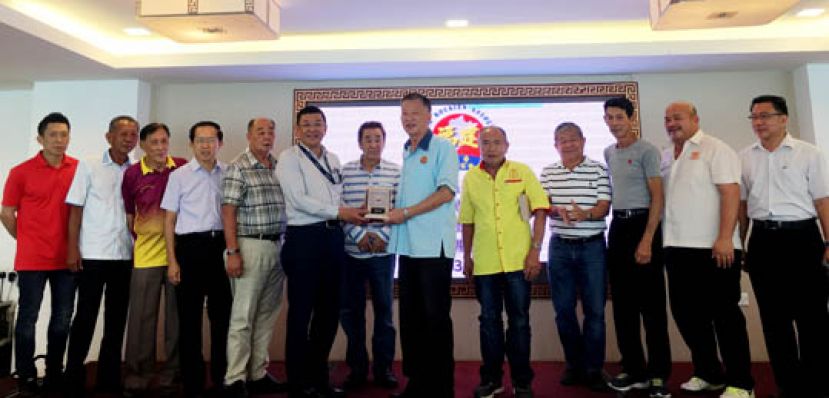 古晋福建公会会长拿督黄良杰（左六）在署理会长黄张金发（左七）等人的见证下赠送纪念品予沙巴根地咬福建会馆主席周亚玖。