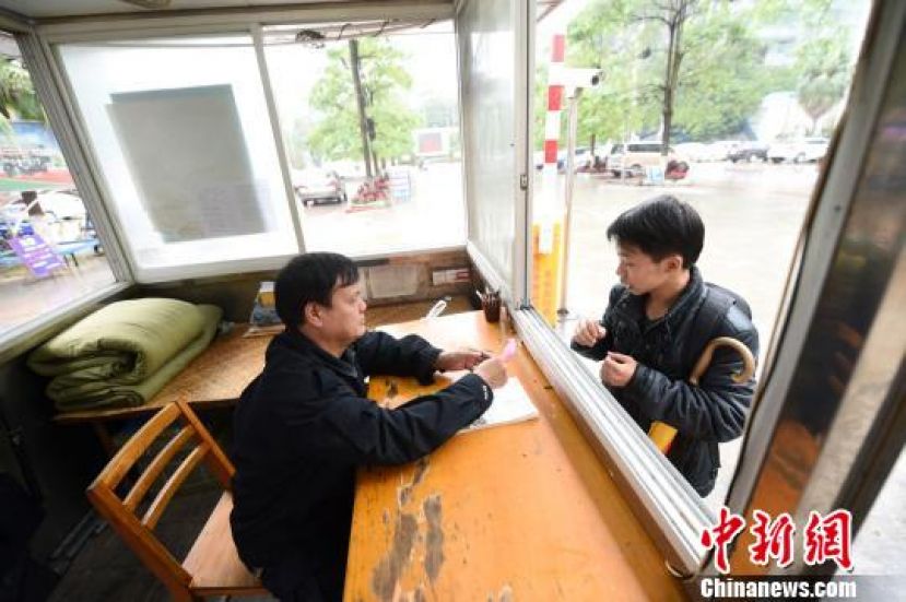陆汉迎在门卫室查看一个学生的外出审批条。