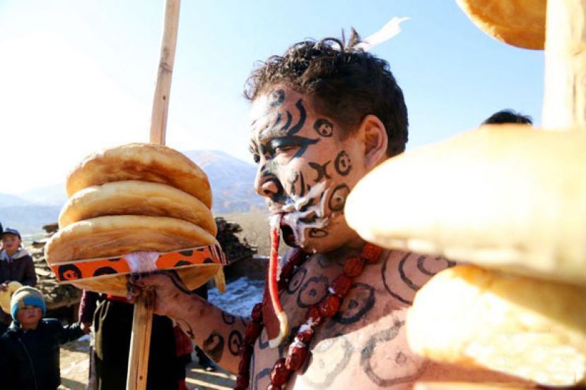 图示：一名&ldquo;于菟&rdquo;嘴叼生肉、手持插有&ldquo;看子&rdquo;（中间空心的烤馍）的柏树杆。